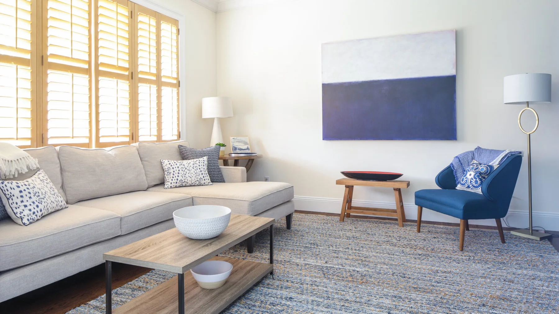 A bright living room with seating, a coffee table, and large windows.