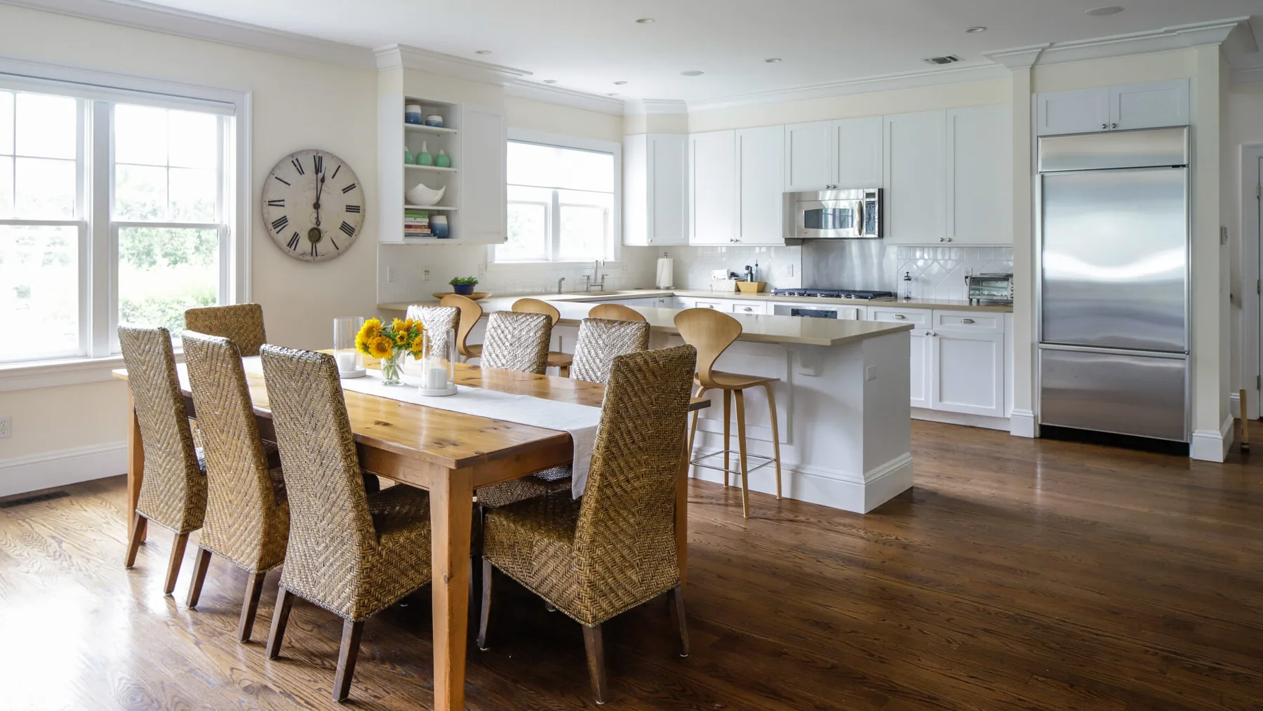 A bright kitchen and dining area with a wooden table and woven seating.