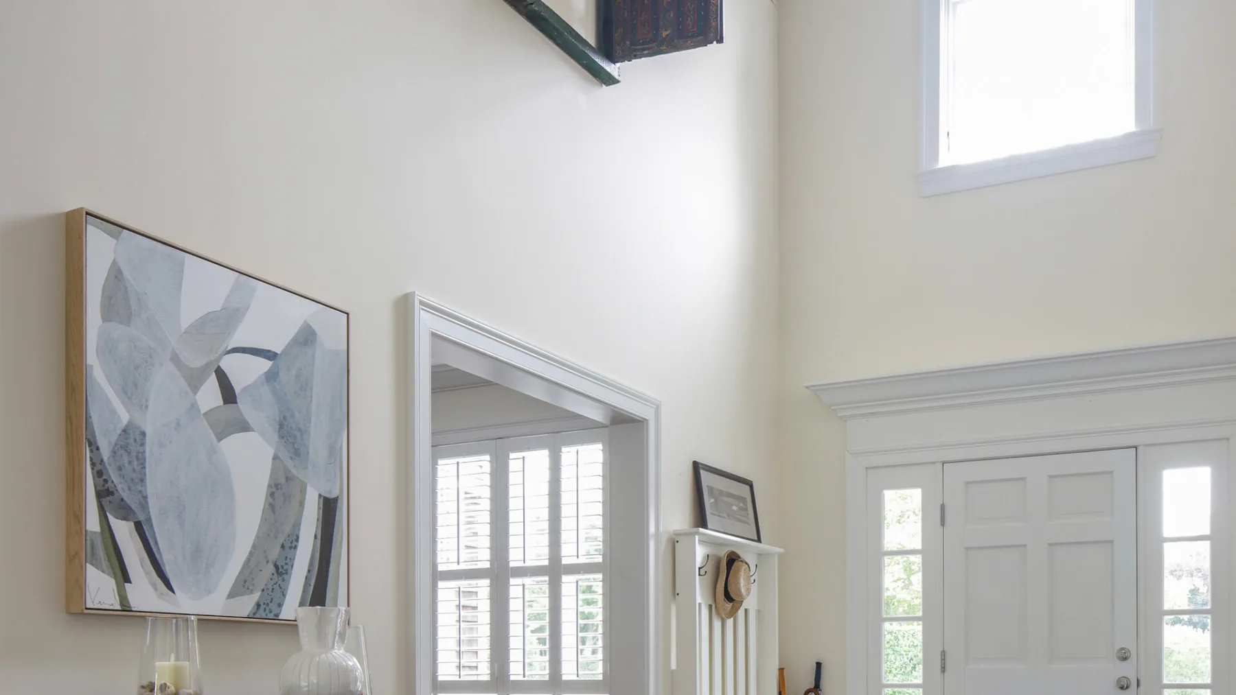 A bright entryway with a white door, sidelights, and framed wall art.
