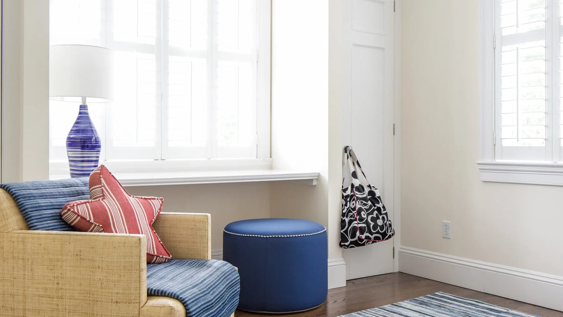 A bright sitting area with a cushioned seating piece beside a blue round ottoman.
