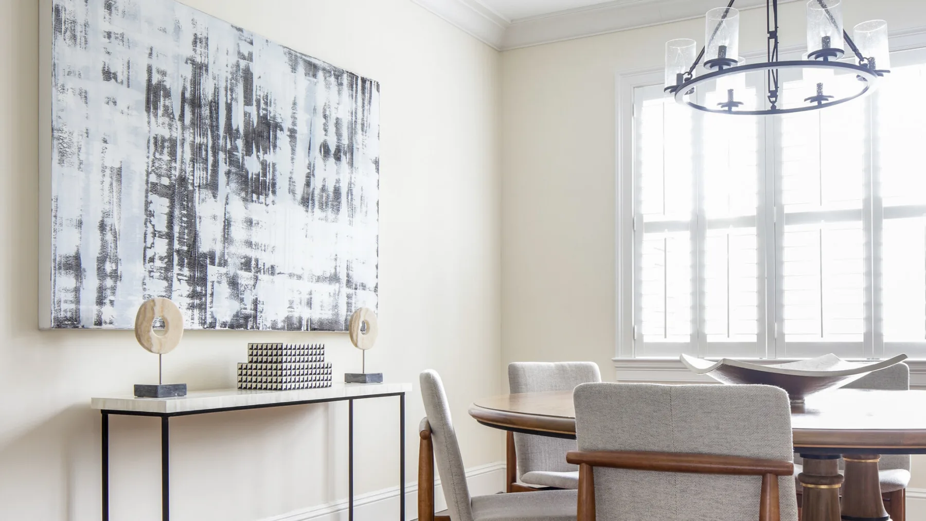 A bright dining room with a table, seating, and a large abstract painting.