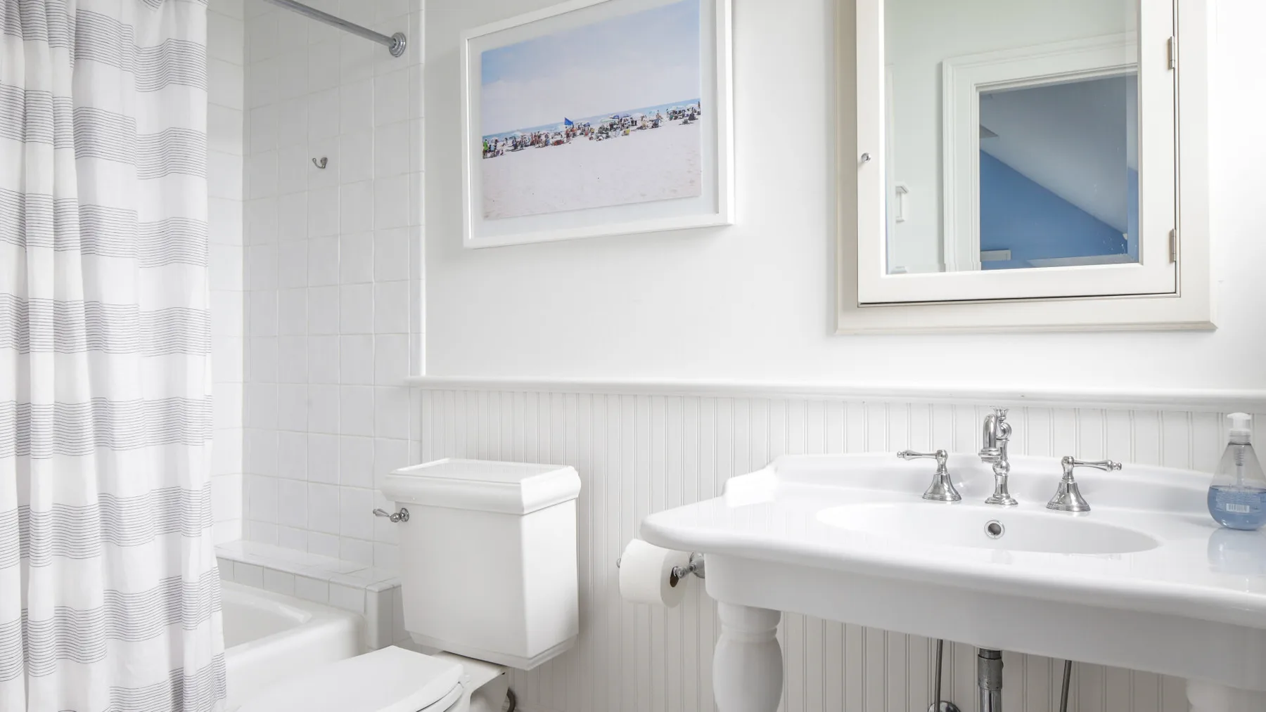 A bright bathroom with a white sink, toilet, and shower curtain.