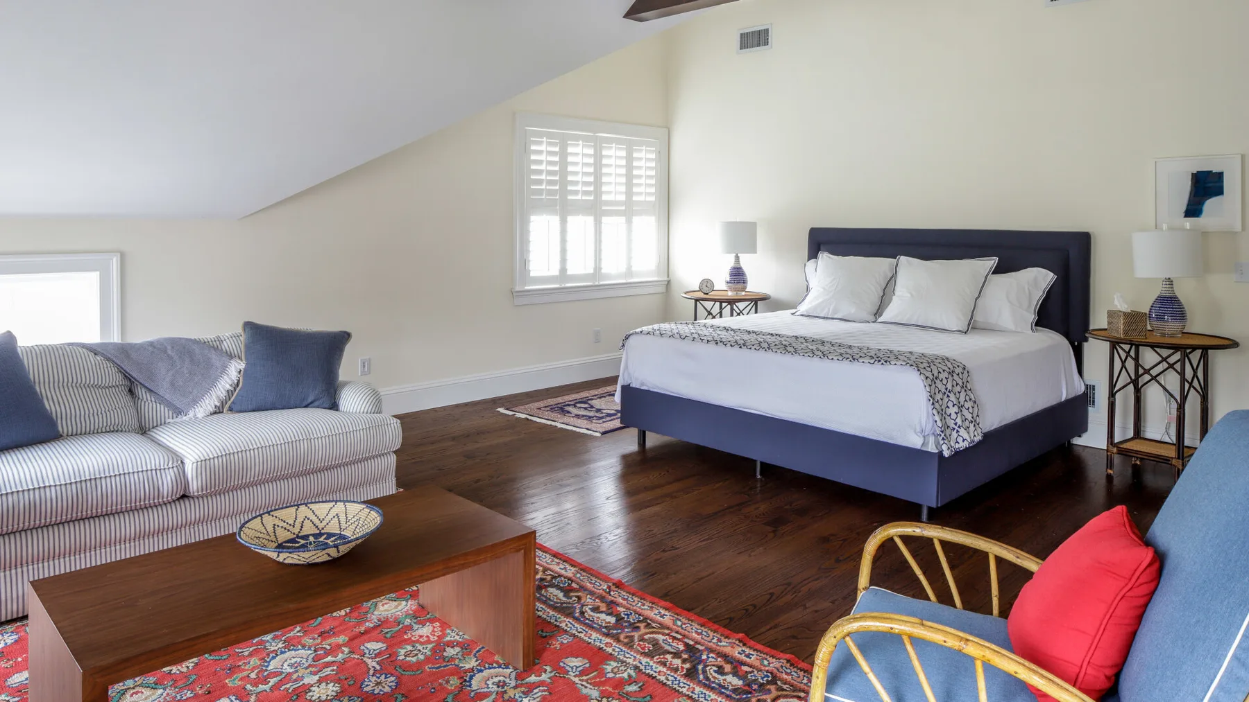A bedroom with a bed, seating, and a patterned rug.