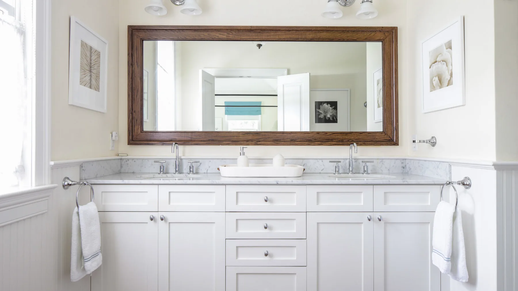A bright bathroom with a long vanity, two sinks, and a large wall mirror.