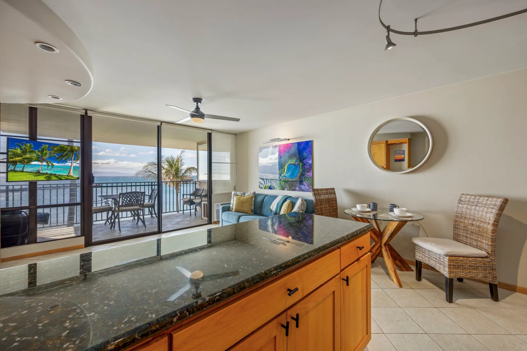 A kitchen island faces a dining area and large windows overlooking the water.