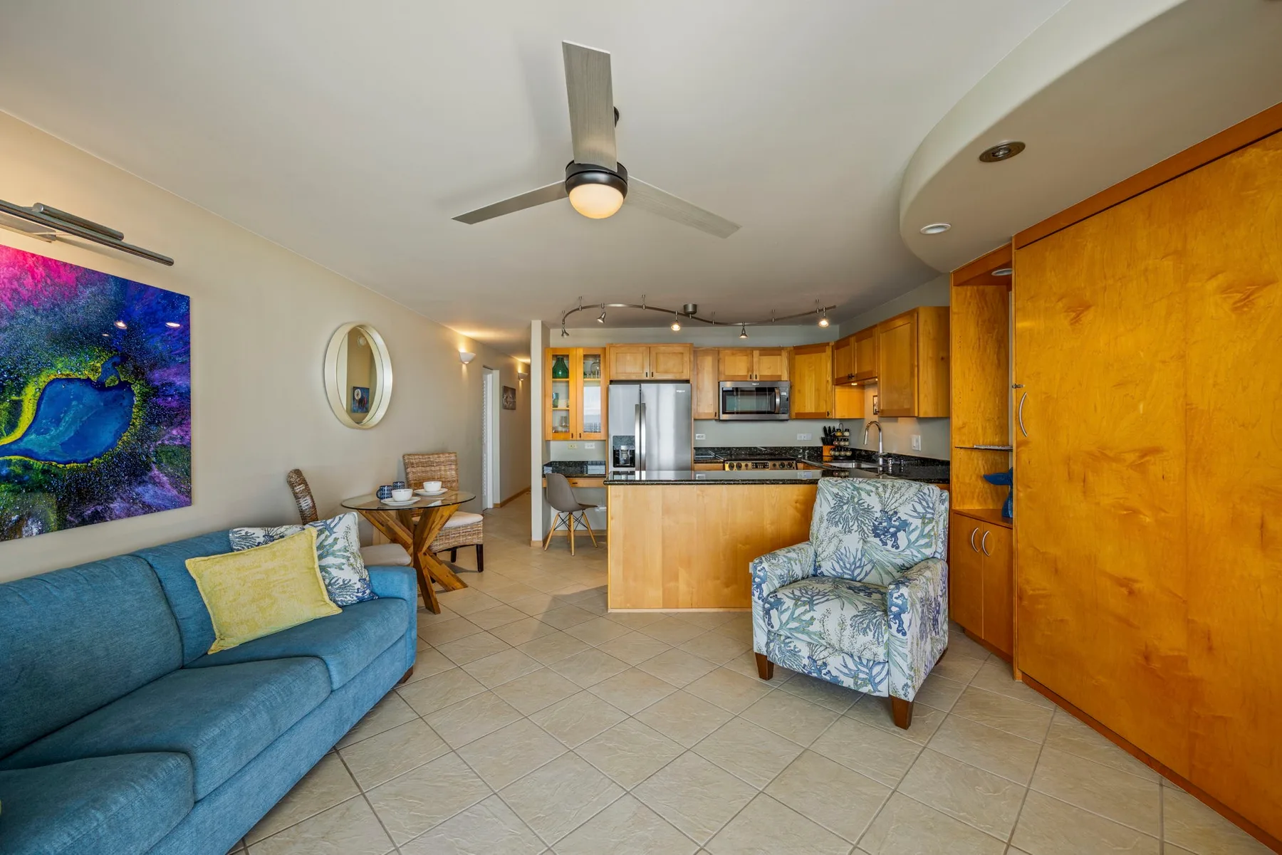 An open-plan living room and kitchen with a blue seating area and wooden cabinetry.