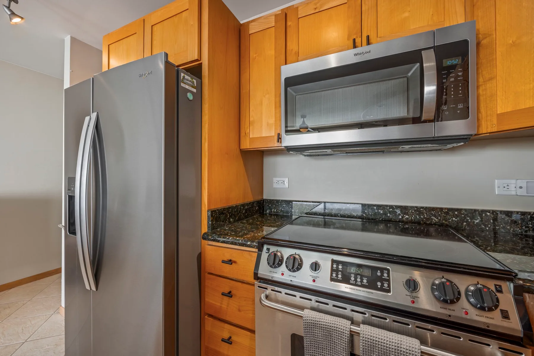 A kitchen with wooden cabinets, a refrigerator, and a stove beneath a microwave.