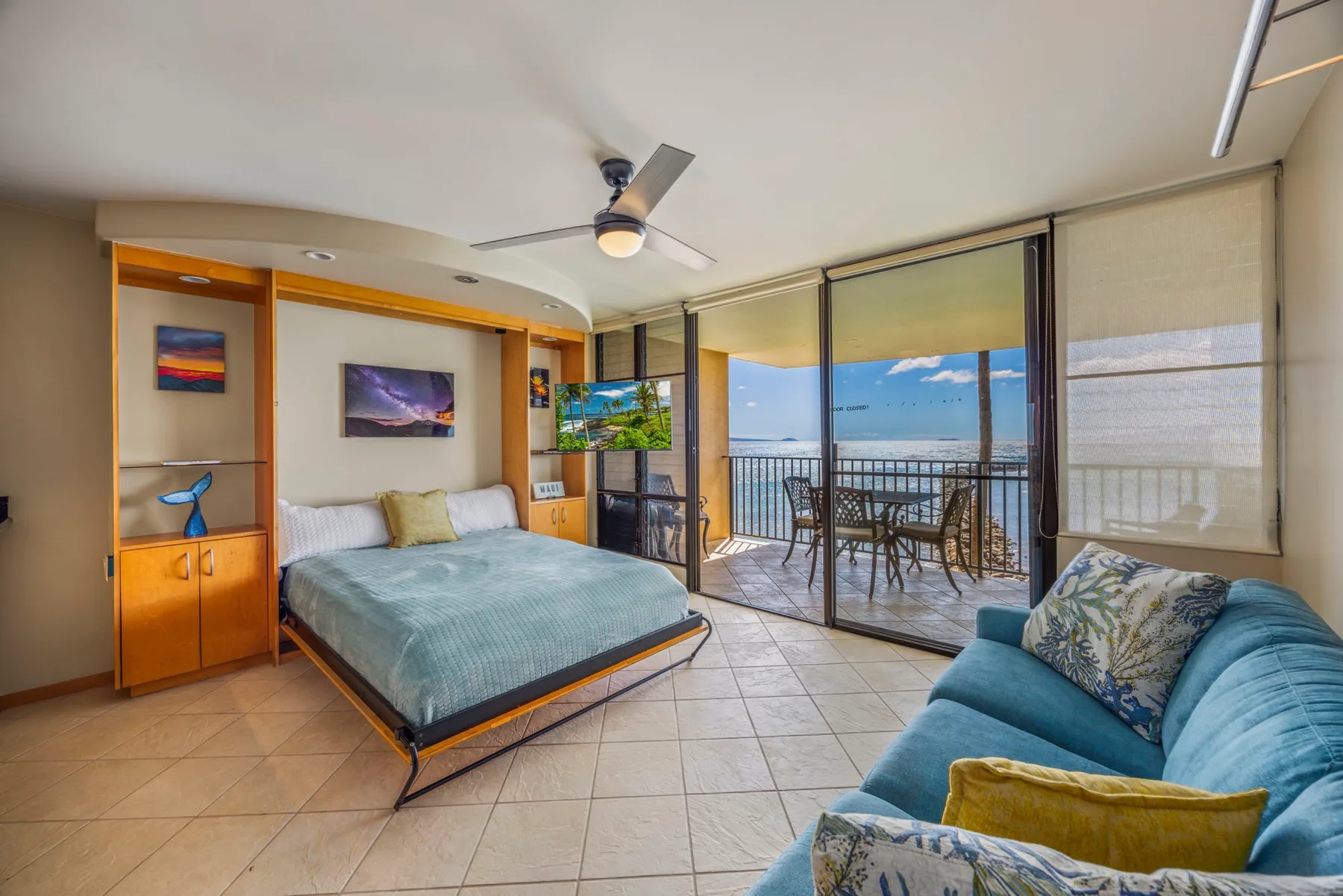A bedroom with a bed and seating beside sliding glass doors opening onto a balcony.