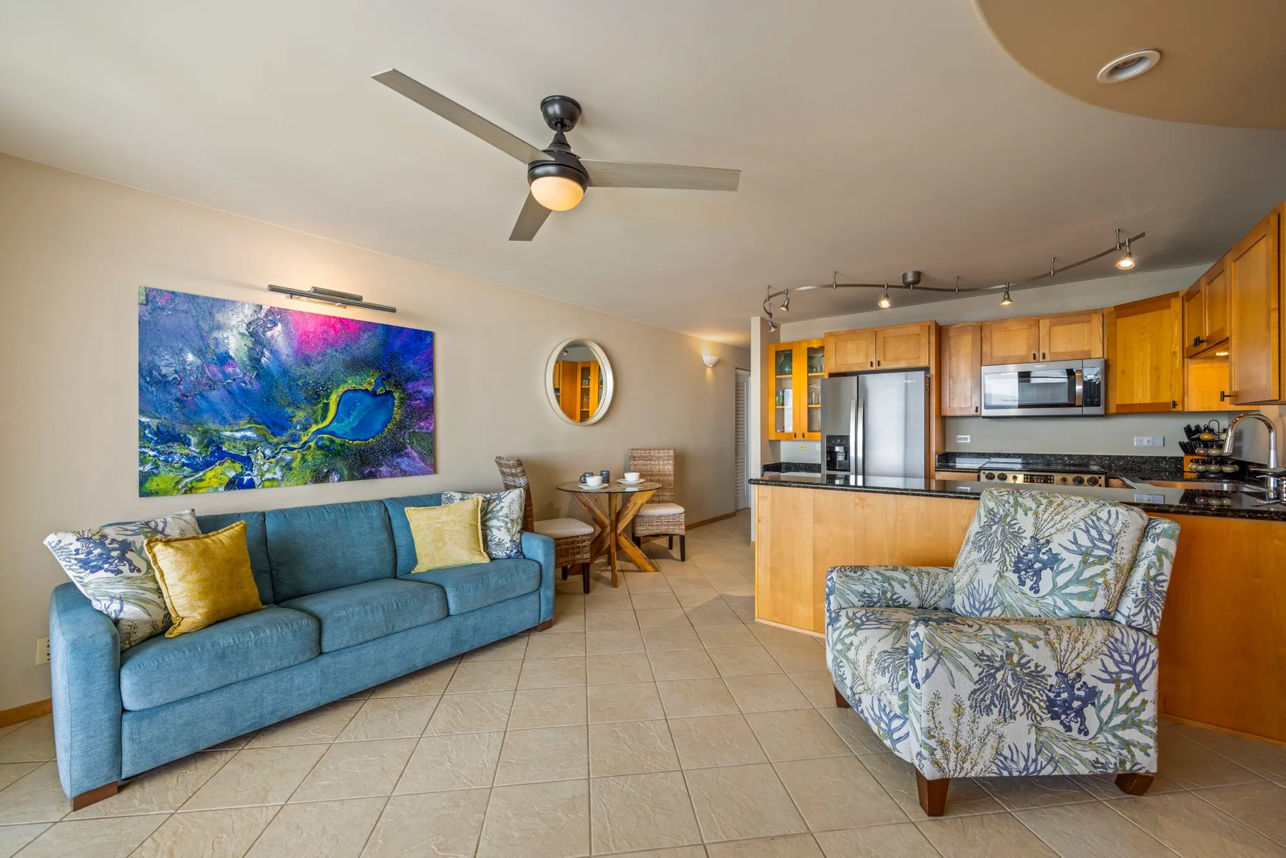 A living room with a blue sofa and an open kitchen.