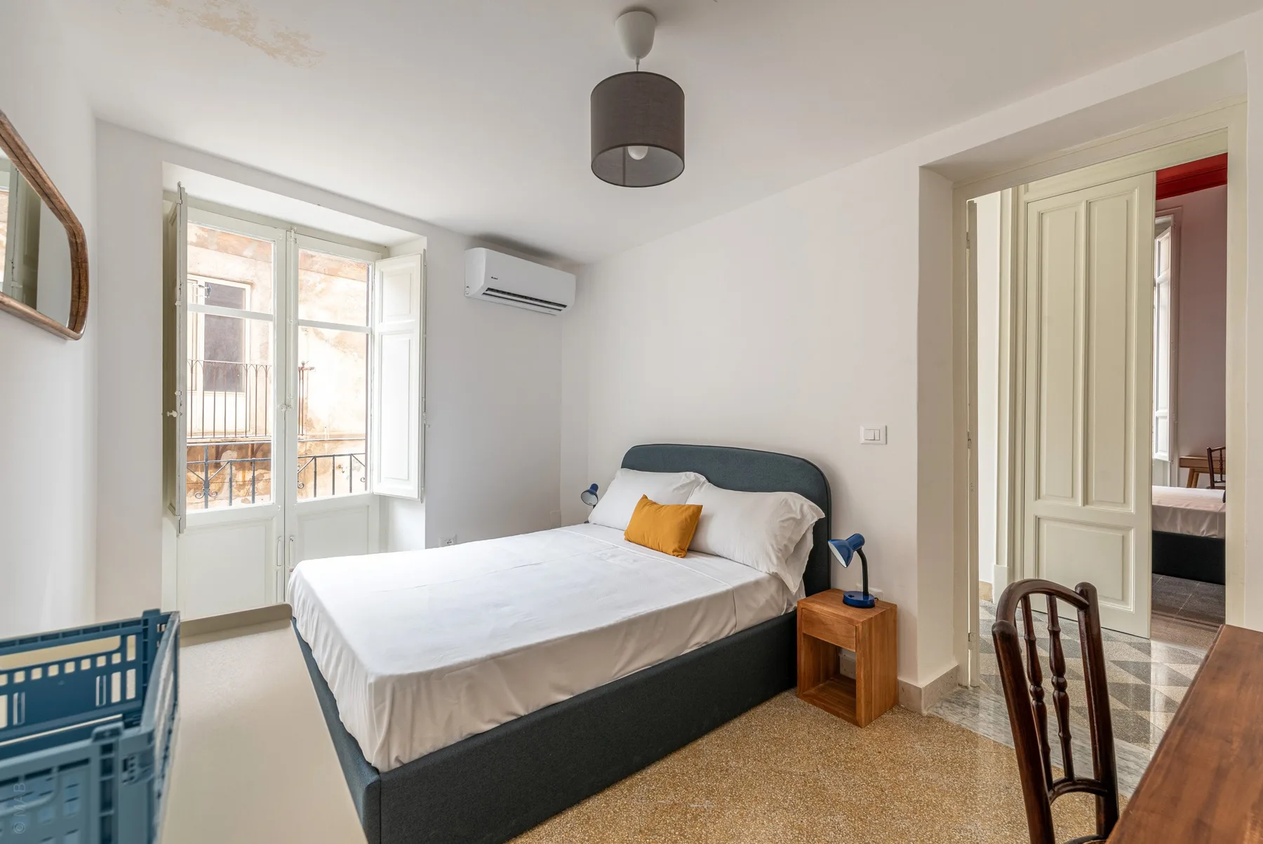 A bedroom with a bed beside a bright window.