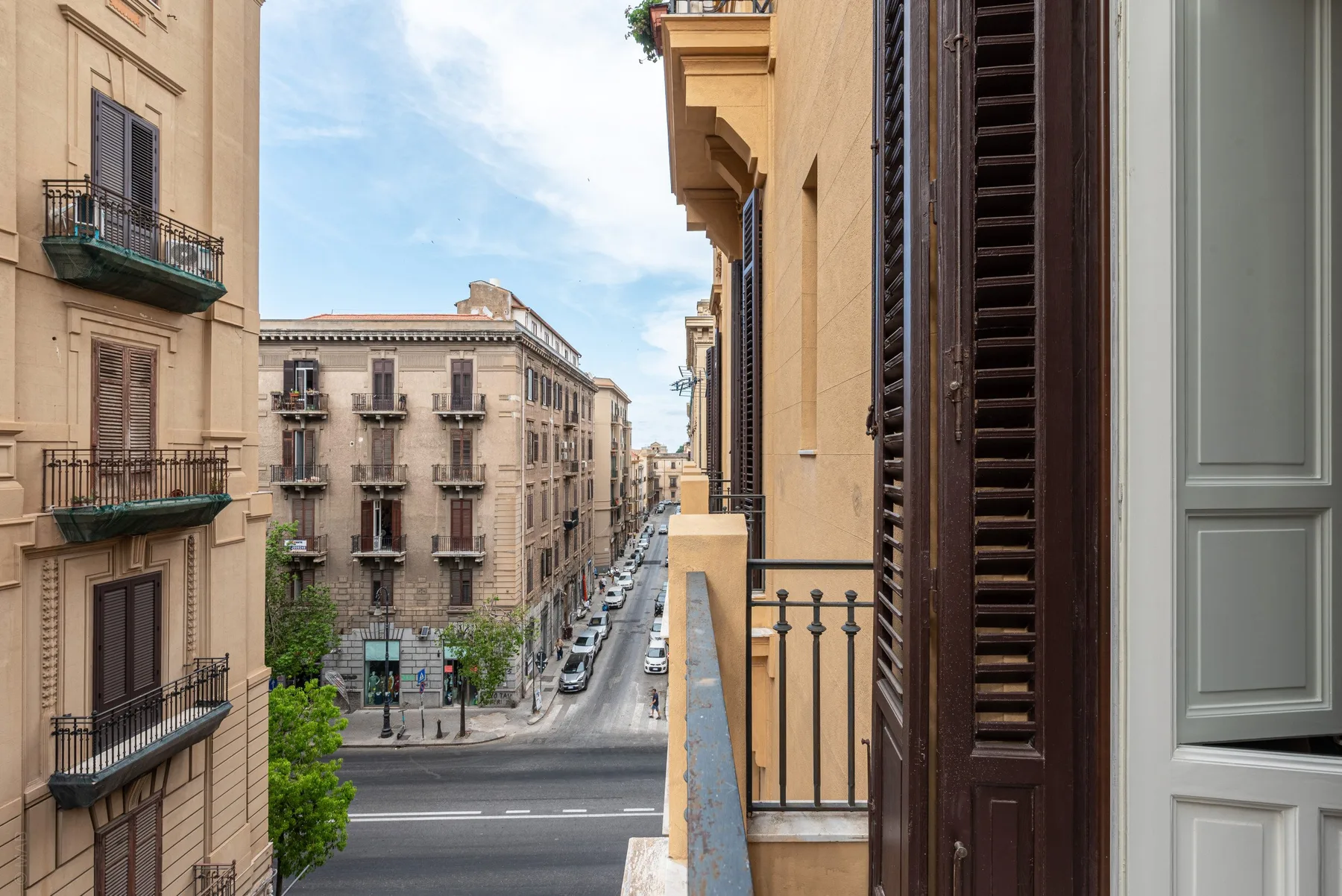 A narrow balcony overlooks a city street lined with apartment buildings.