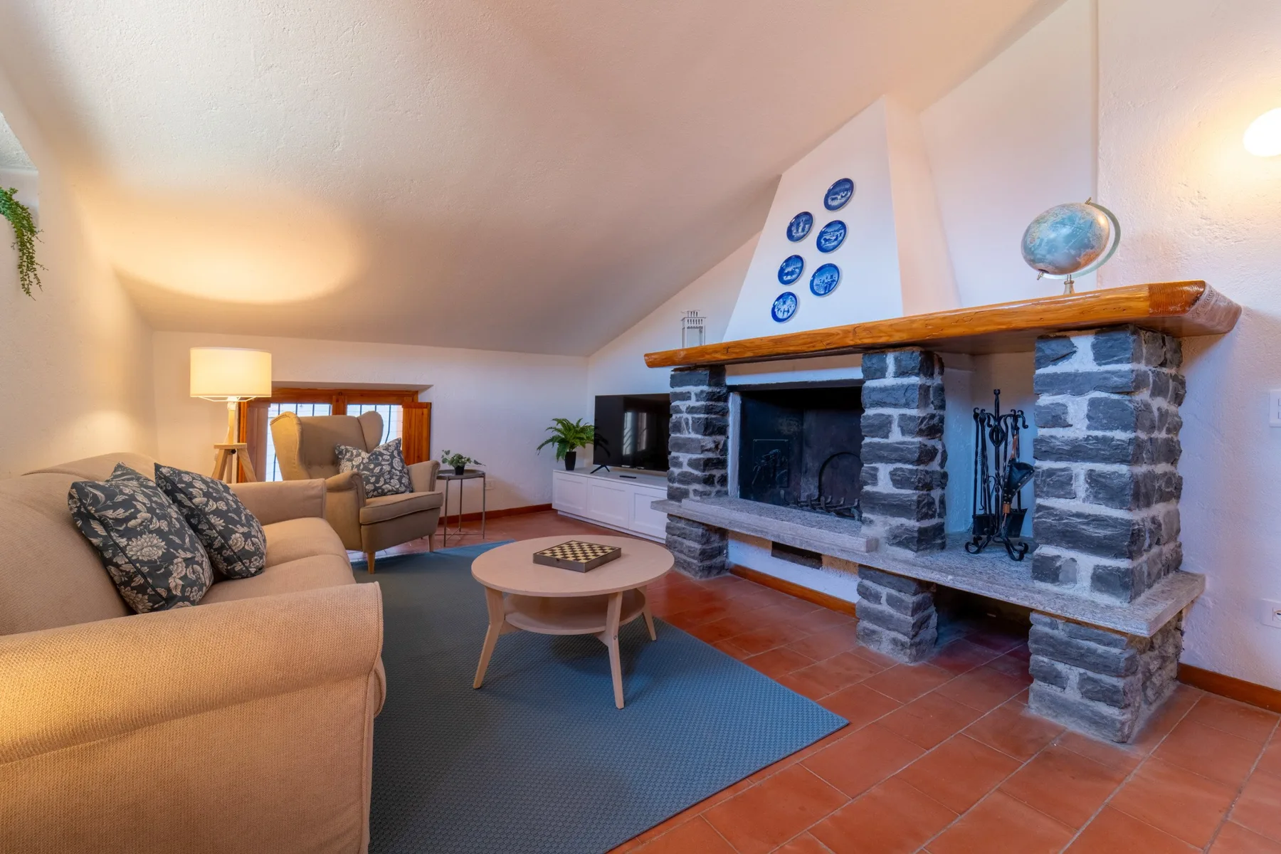 A living room with seating around a large stone fireplace and a coffee table.