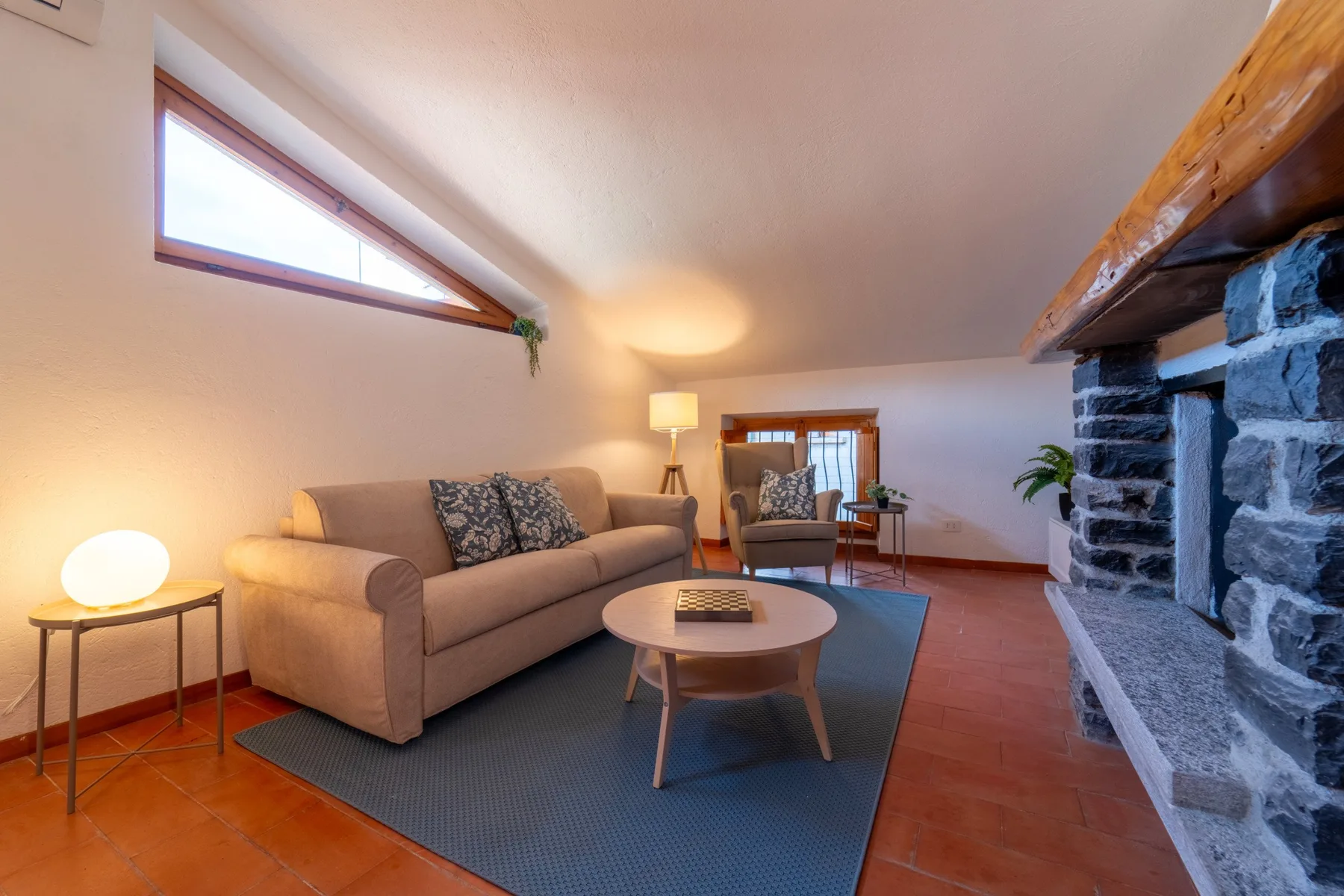 A living room with seating around a coffee table beside a stone fireplace.