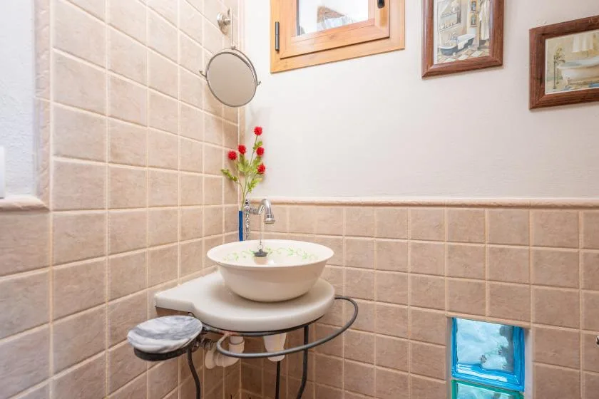 Un lavabo de baño alicatado con una pila redonda y un espejo.
