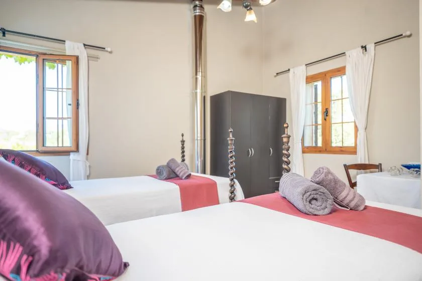 Un dormitorio con camas, un armario oscuro y ventanas iluminadas.