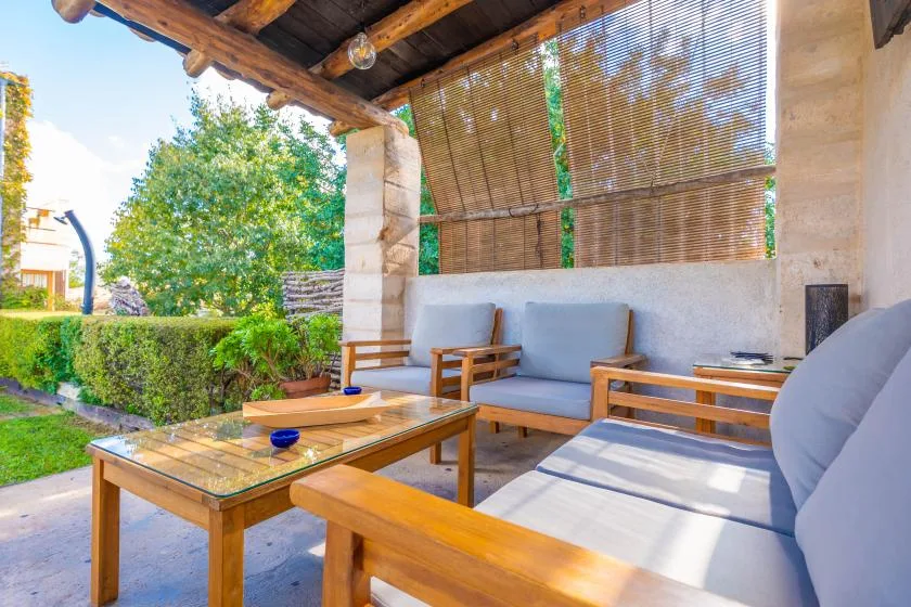 Una zona de estar exterior cubierta con bancos acolchados y una mesa de centro de madera.
