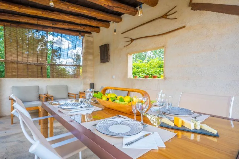Comedor con la mesa puesta y vegetación visible por la ventana.