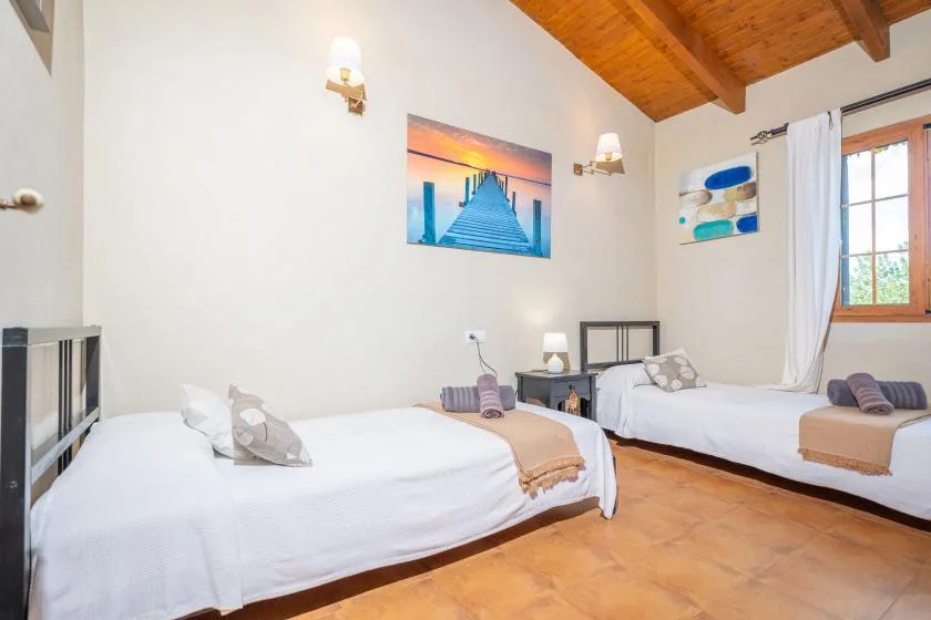 Un dormitorio con dos camas, arte en la pared y un techo inclinado de madera.