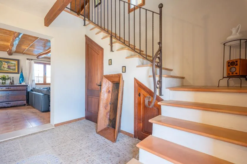 Un recibidor interior con una escalera de madera y vista a la sala contigua.
