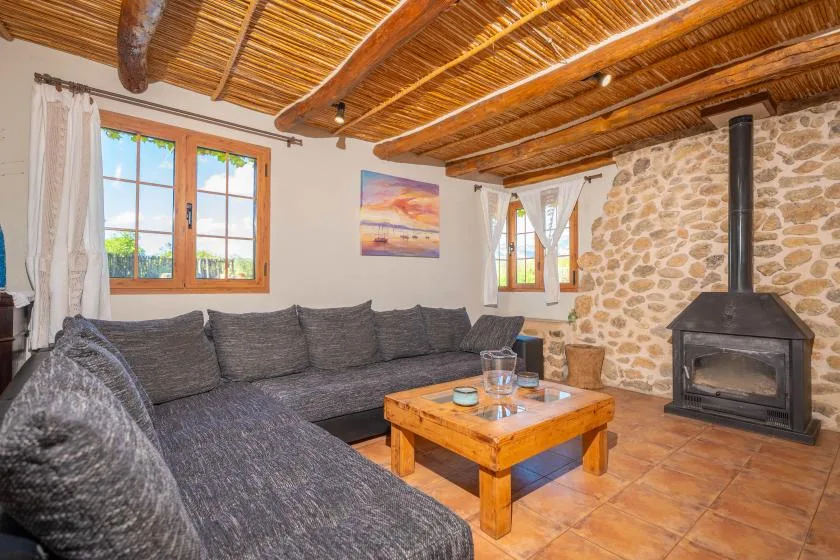 Una sala de estar con asientos grises, una mesa de centro de madera y una chimenea independiente.