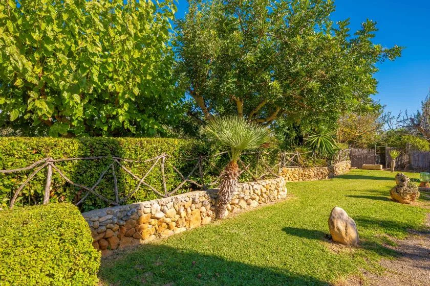 Un jardín ajardinado con setos recortados, árboles y césped.