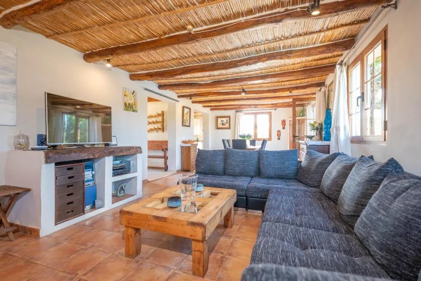 Una sala de estar con asientos grises, una mesa de centro de madera y un televisor.