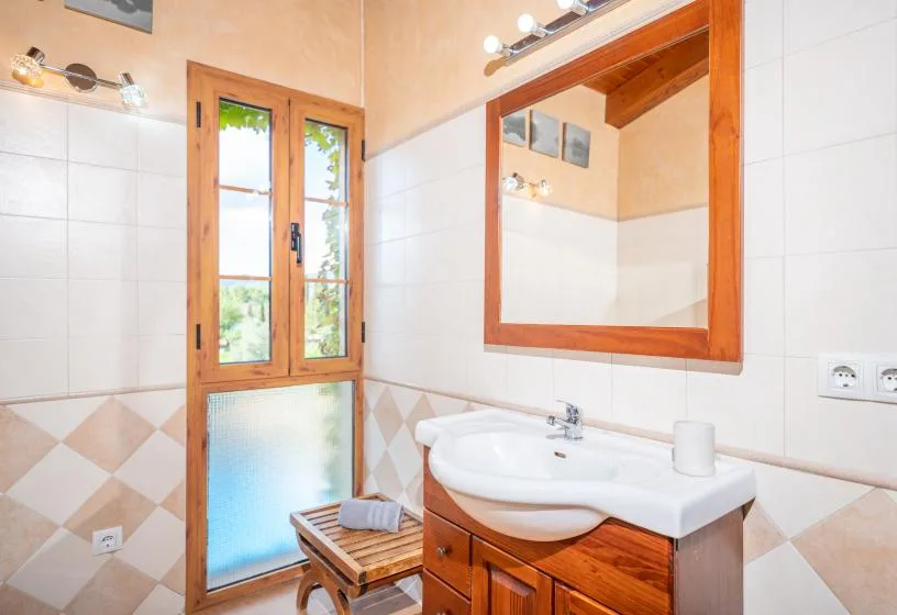 Un baño con lavabo, una ventana con marco de madera y un espejo grande.