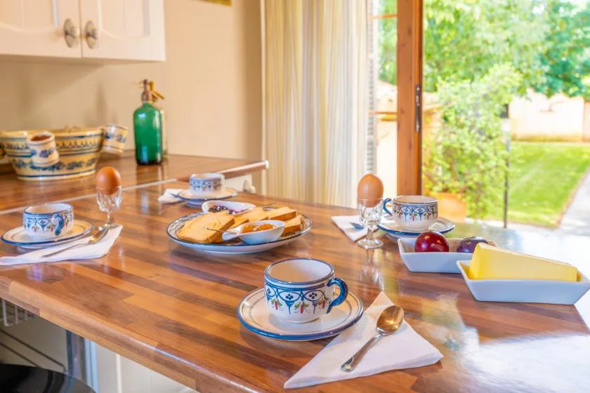 Una mesa de comedor está puesta con vajilla estampada junto a una puerta abierta al jardín.