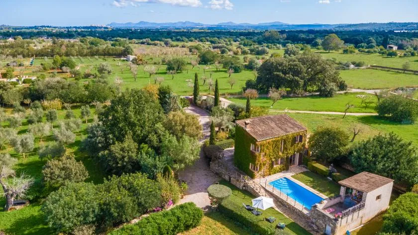 Una vista aérea muestra una propiedad rural con piscina rodeada de campos verdes.