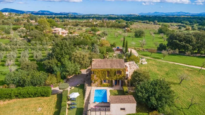 Vista aérea de una casa rural con piscina y campos verdes.
