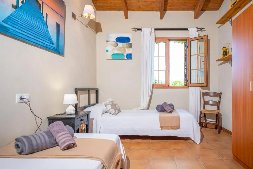 Un dormitorio luminoso con dos camas y una ventana abierta.