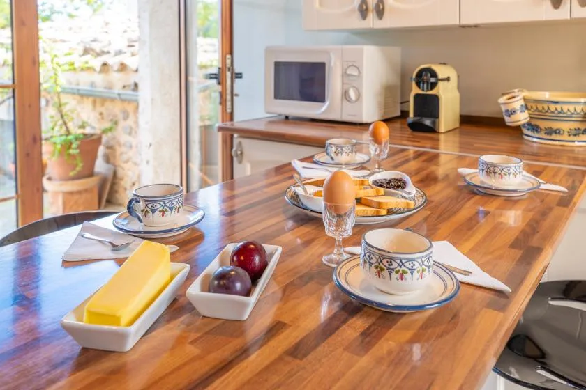 Una mesa de cocina está puesta con tazas y comida de desayuno, junto a un microondas.