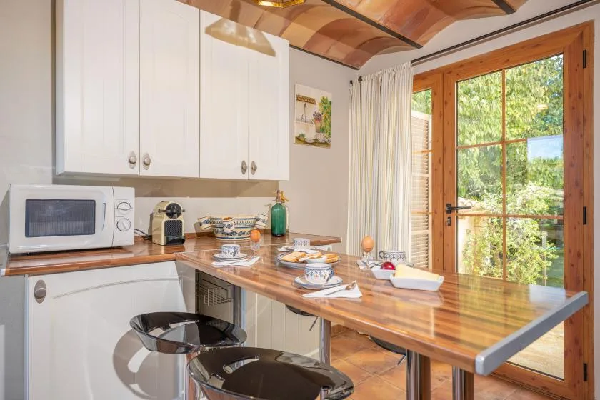 Una cocina luminosa con una encimera de madera, armarios blancos y una puerta de cristal.