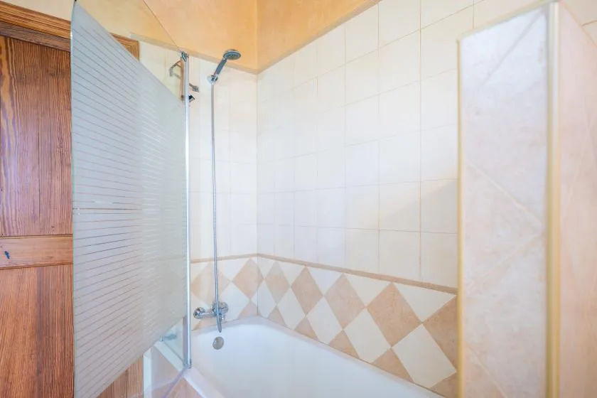 Un baño alicatado con bañera y grifo de ducha.