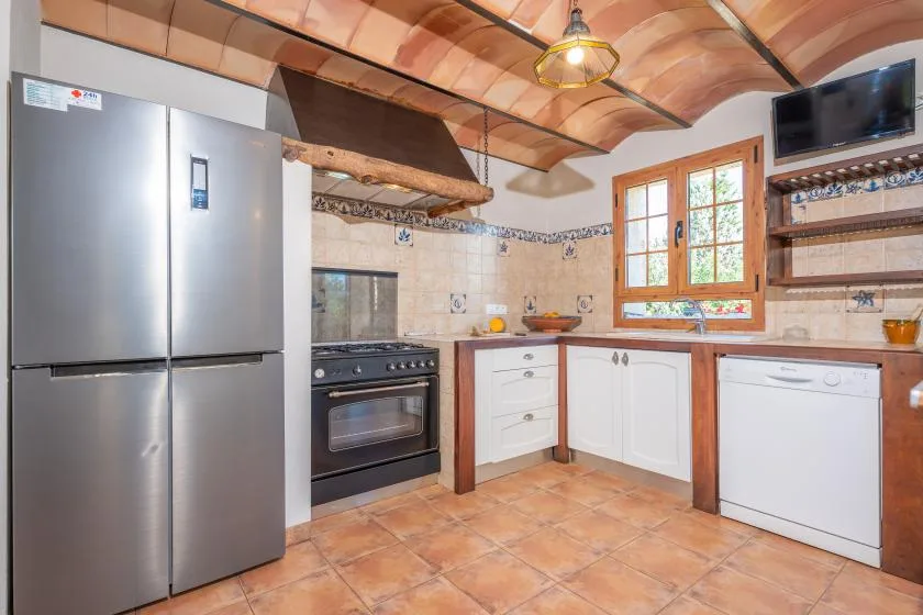 Una cocina con refrigerador, estufa y una ventana con marco de madera.
