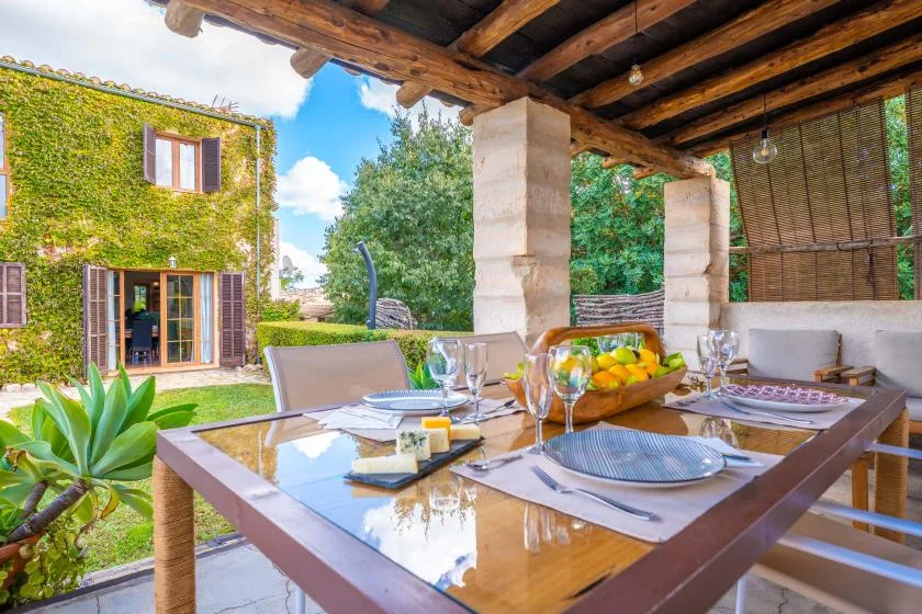 Comedor exterior cubierto con una mesa puesta junto a un jardín.