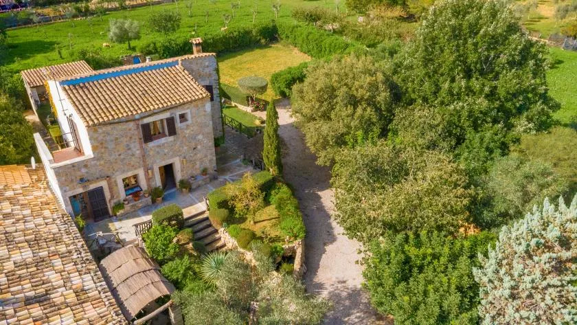 Una casa de piedra se encuentra junto a un sendero de jardín y vegetación.