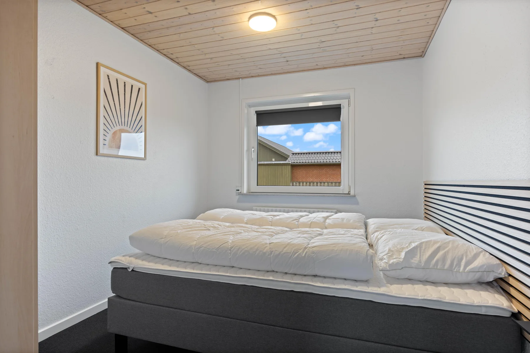 Un dormitorio con una cama doble bajo una ventana pequeña.
