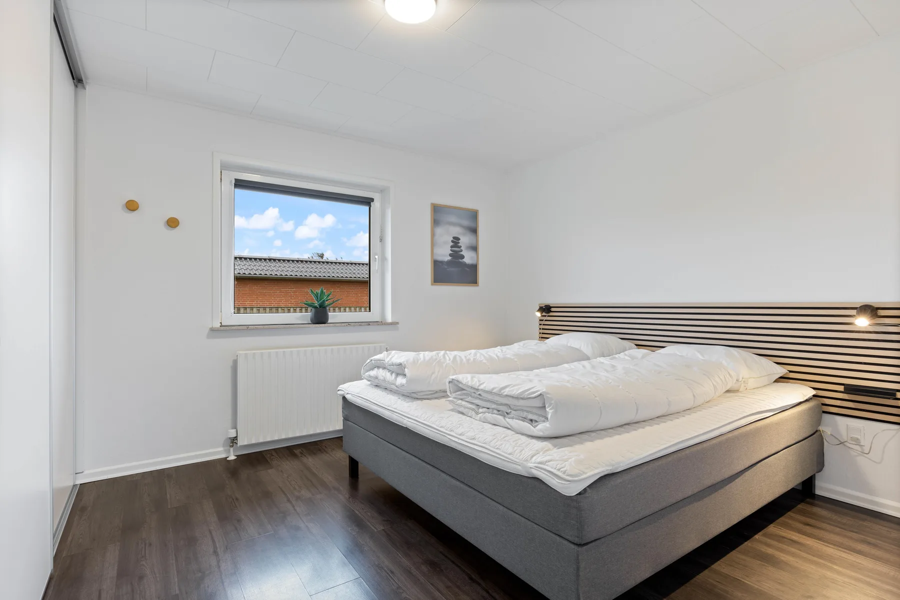 Un dormitorio luminoso con una cama doble bajo una lámpara de lectura en la pared.