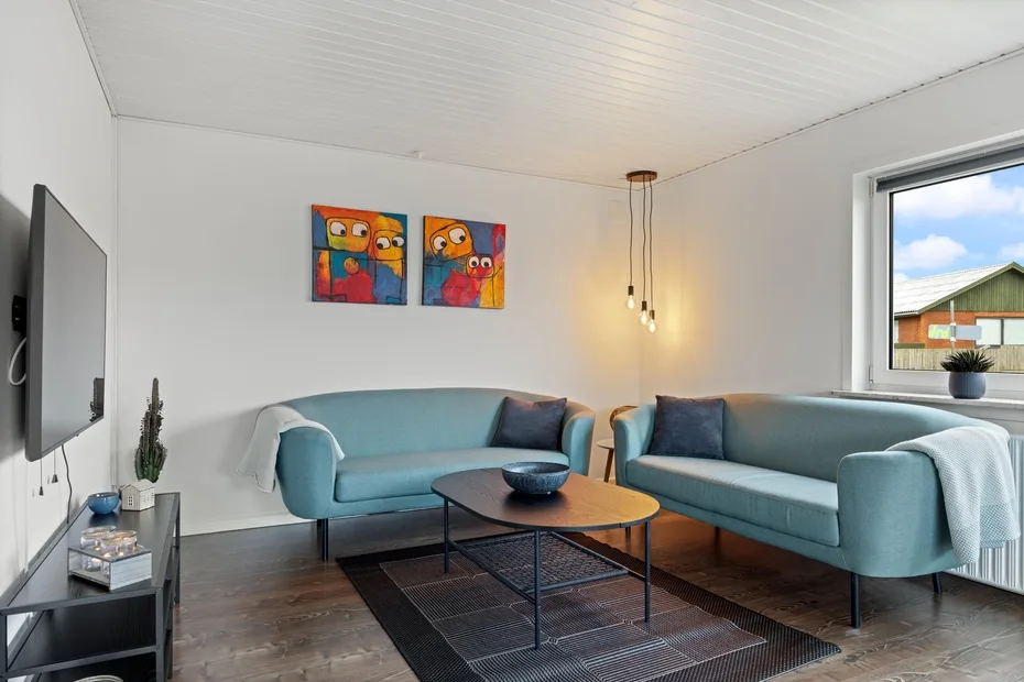Una sala luminosa con asientos azules, una mesa de centro y arte colorido en la pared.