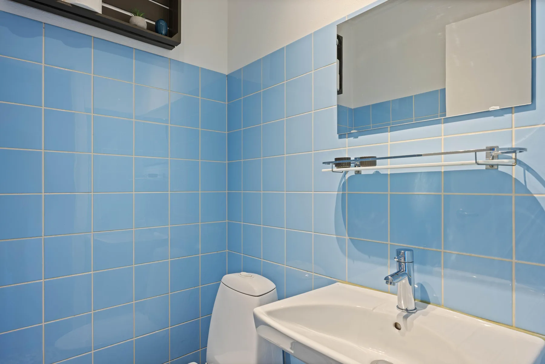 Un baño con azulejos, lavabo, espejo e inodoro.