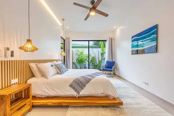 Un dormitorio luminoso con una cama de madera y puertas corredizas de vidrio frente a plantas.