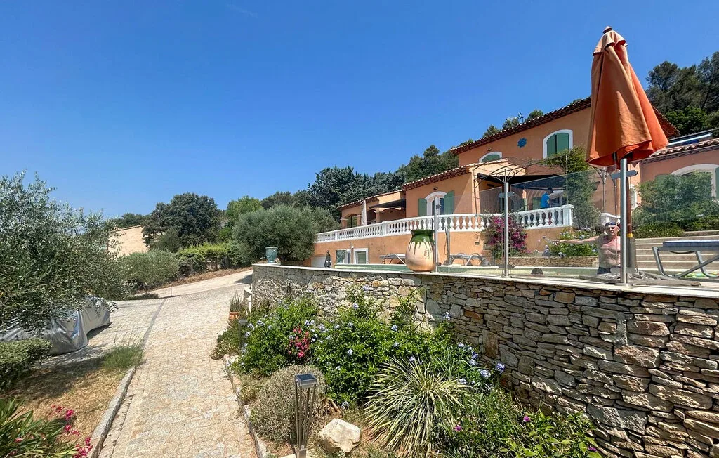 Una casa color terracota está junto a un sendero de piedra y parterres con plantas.