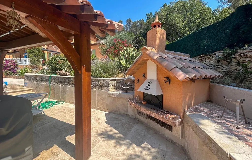 Un patio exterior cubierto con una barbacoa de obra y una zona para sentarse.