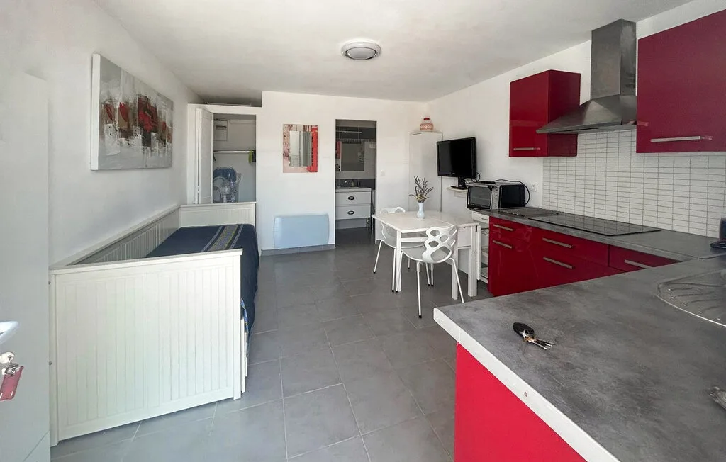 Una cocina y comedor compactos con gabinetes rojos y una mesa pequeña.
