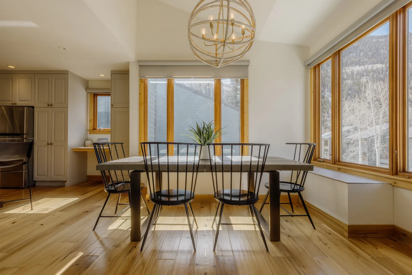 Comedor con una mesa y asientos junto a grandes ventanas.