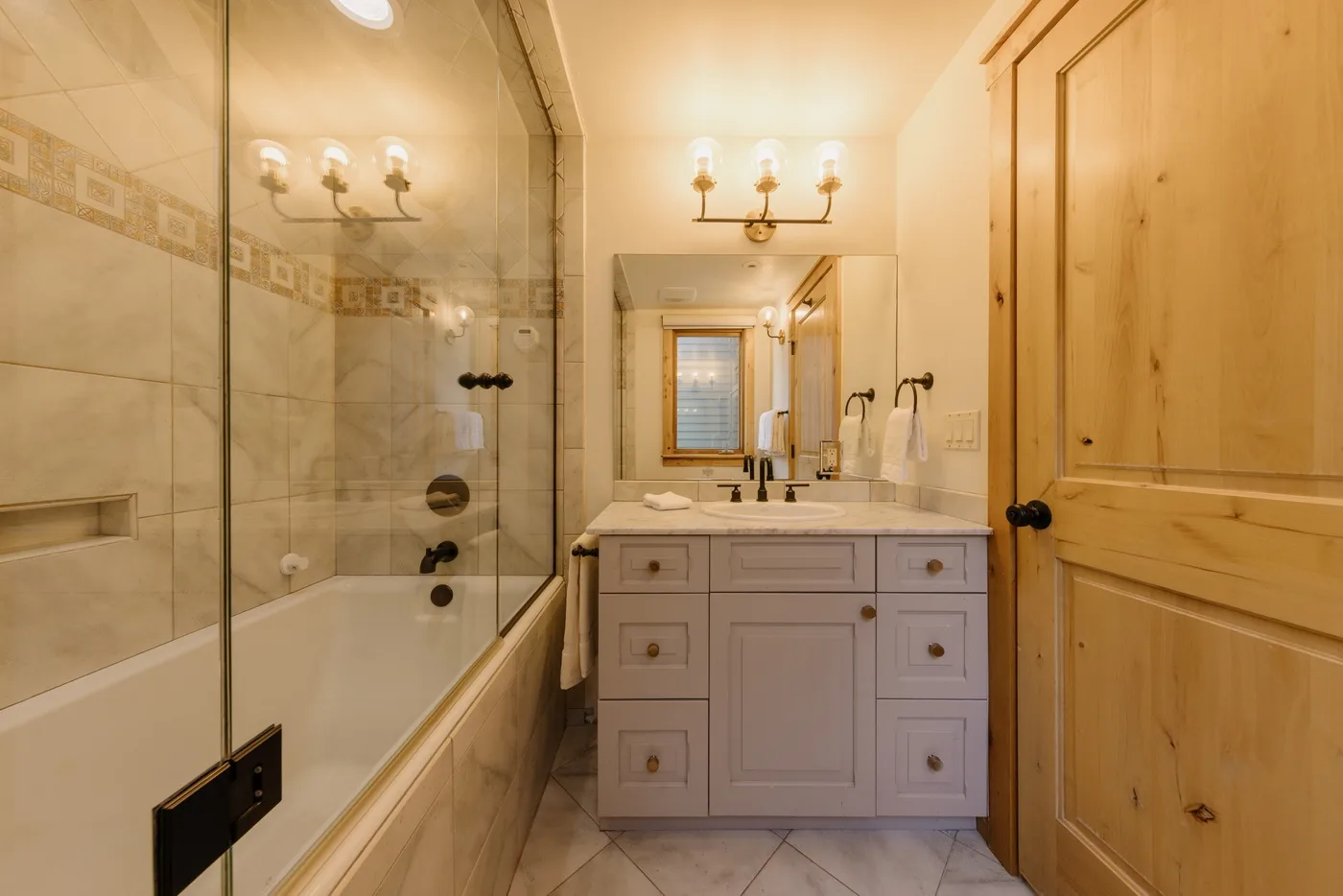 Un baño con lavabo, espejo y ducha con mampara de vidrio.