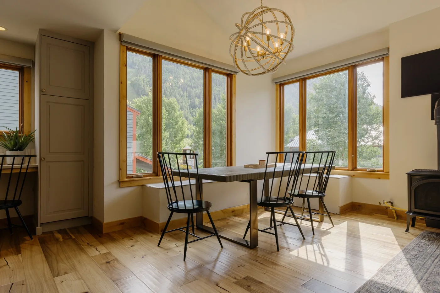 Un comedor con una mesa y asientos junto a grandes ventanas.