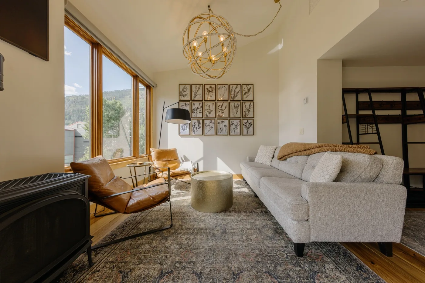 Una sala de estar luminosa con asientos alrededor de una mesa de centro junto a grandes ventanas.