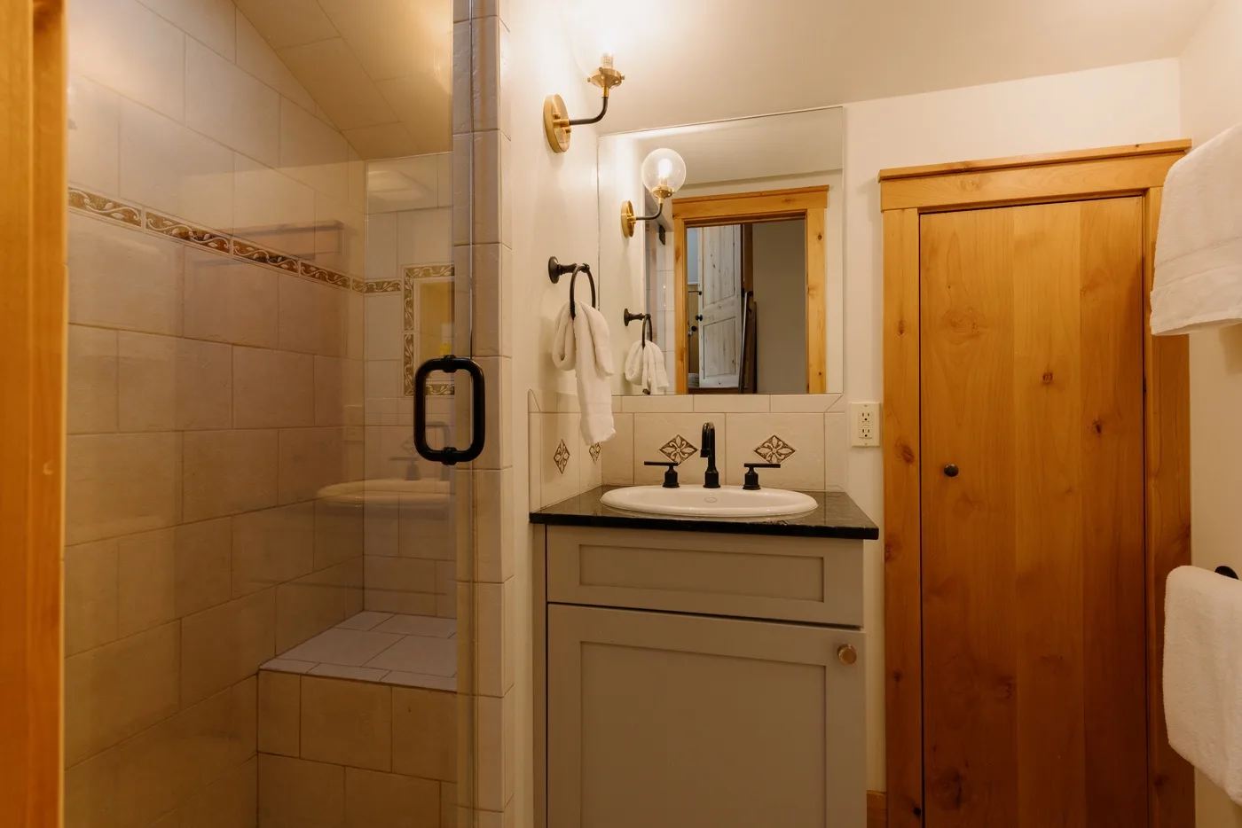 Un baño con una ducha de vidrio y un tocador bajo un espejo.